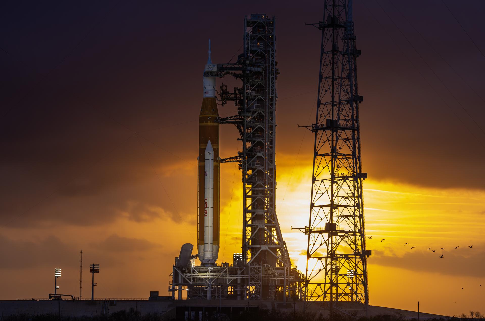 This image shows a sunset of NASA’s SLS (Space Launch System) and Orion spacecraft at NASA’s Kennedy Space Center. NASA's massive Crawler-Transporter, upgraded for the Artemis program, carried the powerful SLS rocket and Orion spacecraft on the Mobile Launcher from the Vehicle Assembly Building to Launch Pad 39B at Kennedy Space Center in preparation for the Artemis II mission.